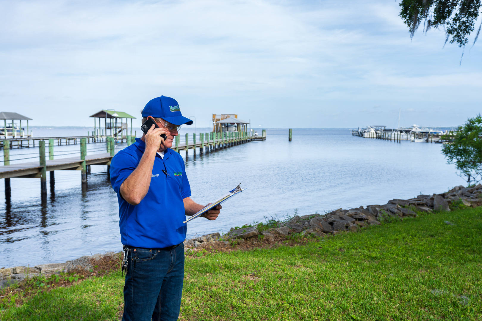 commercial maintenance account manager inspecting large shade trees waterfront