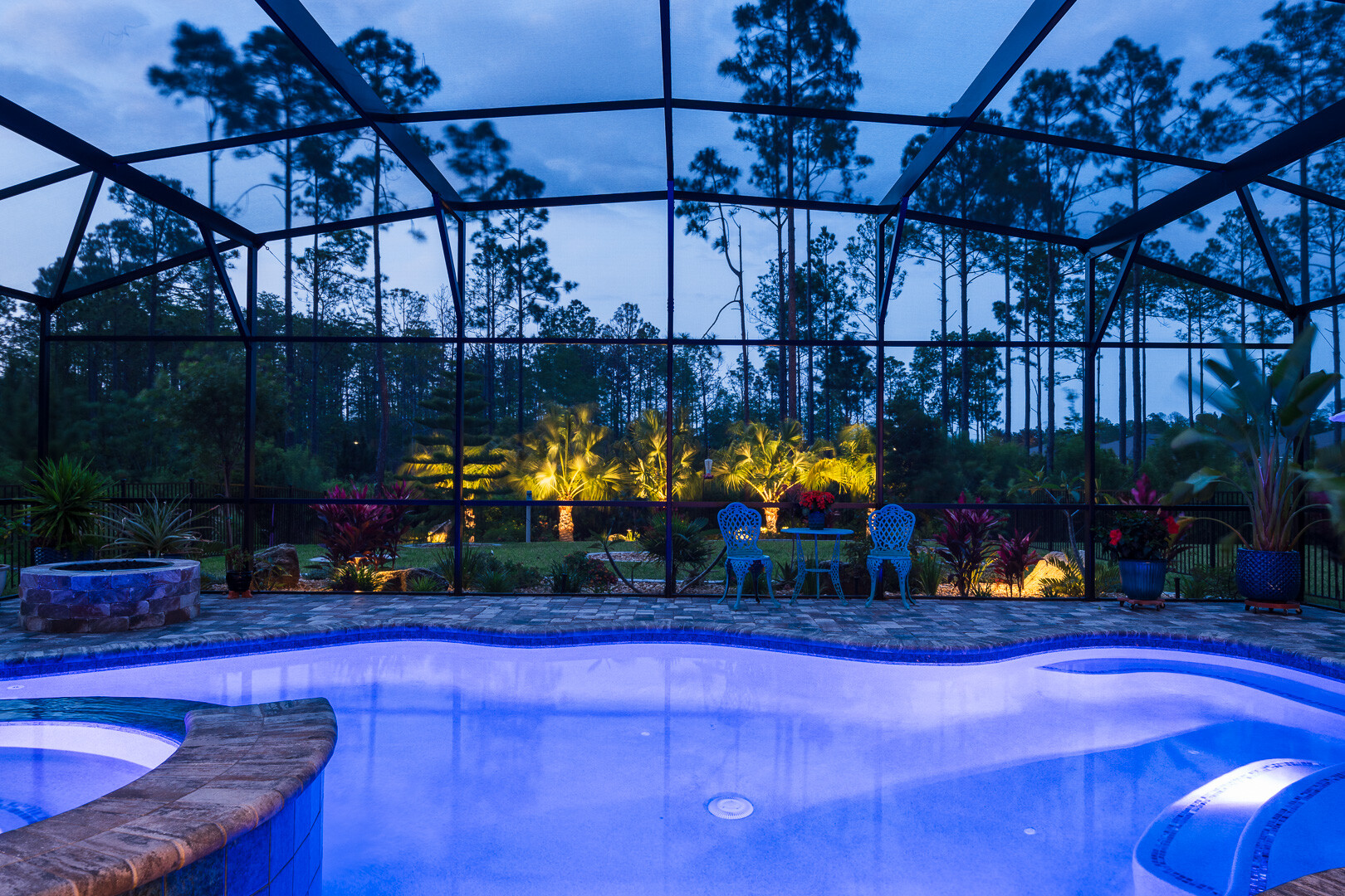 covered pool house with pool decking pavers planting bed and landscape lighting in background 2