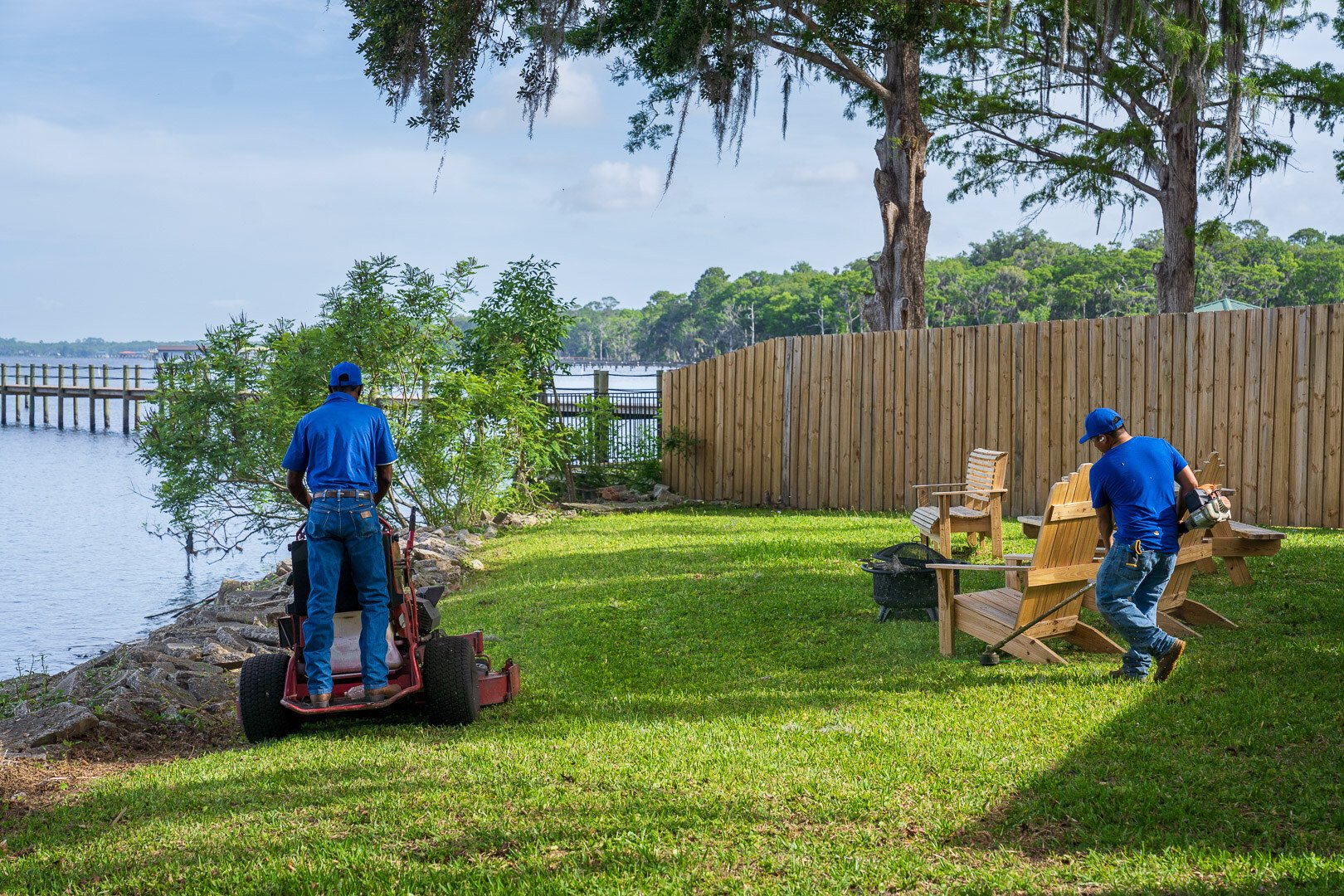 commercial maintenance team mowing and trimming waterfront lawn