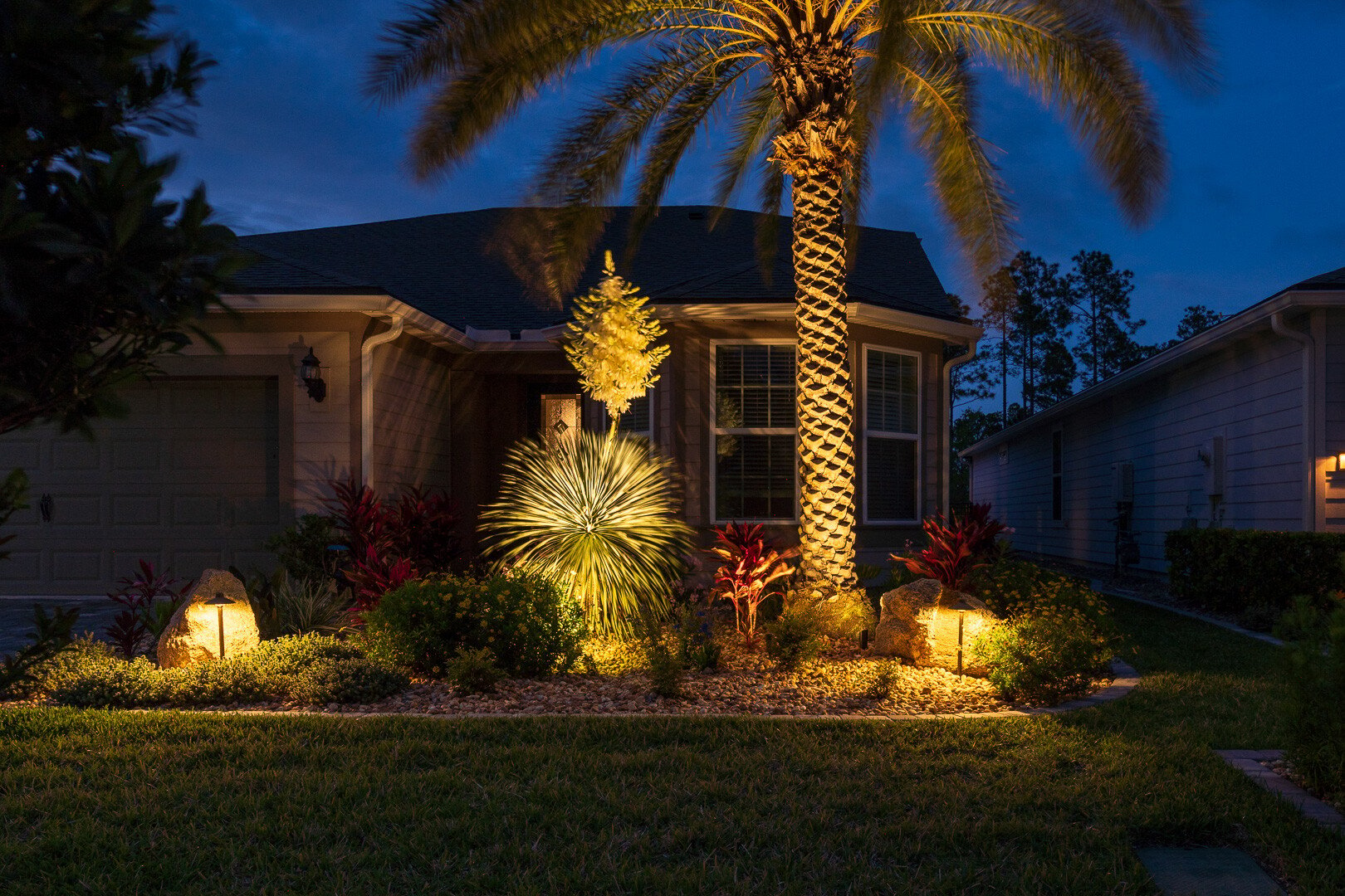 landscape lighting illuminating a planting bed in front of a florida home