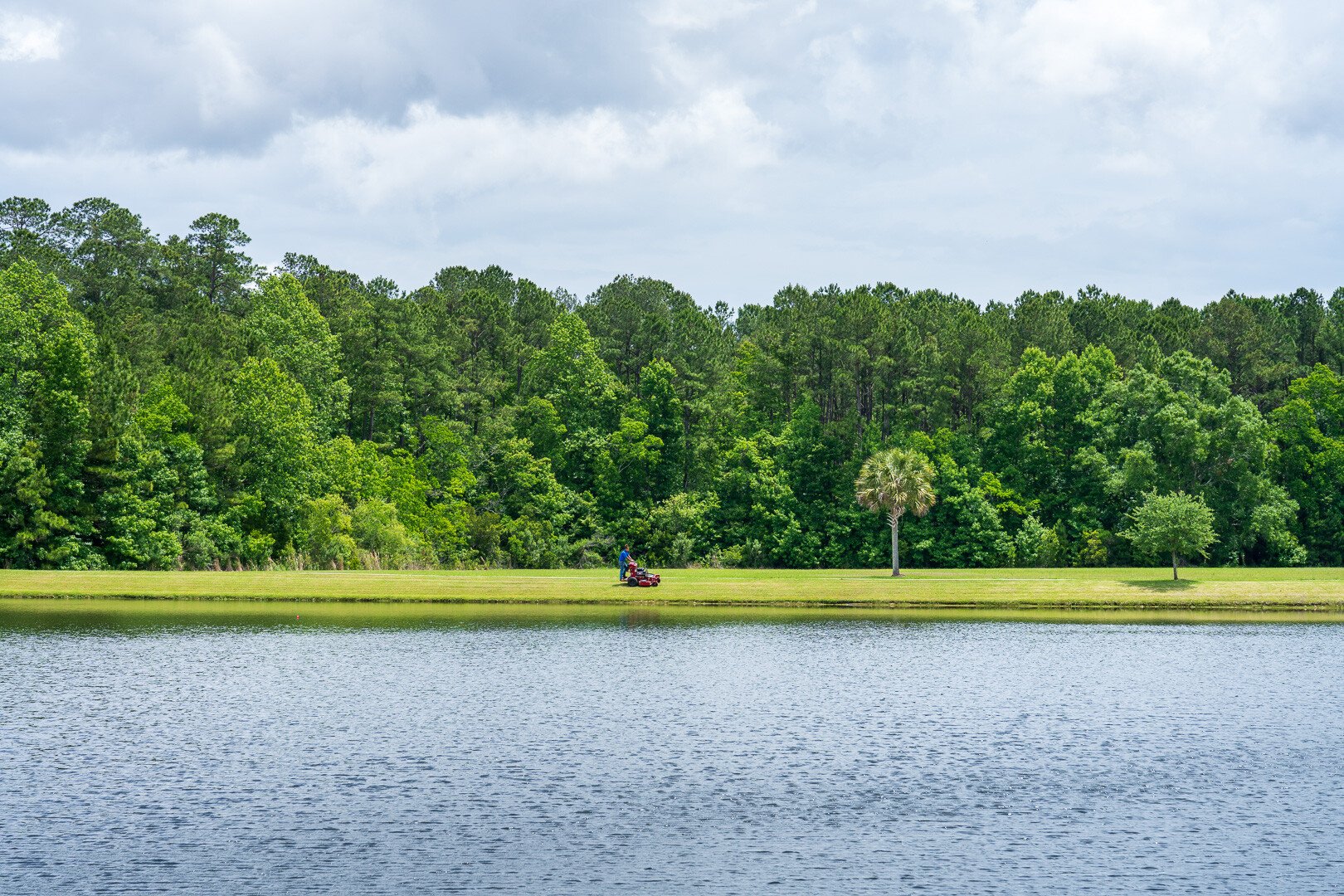 maintenance technician mowing lawn space waterfront