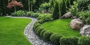Properly graded garden lawn featuring a dry river rock drainage swale to direct water flow and prevent yard erosion.